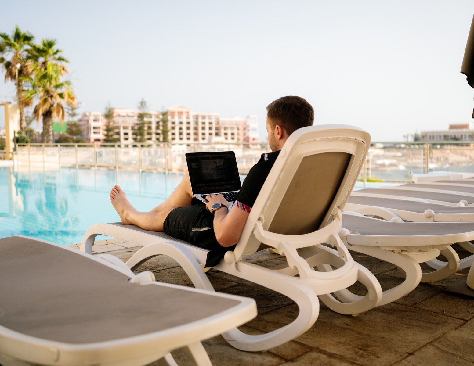 man on sun lounger using laptop